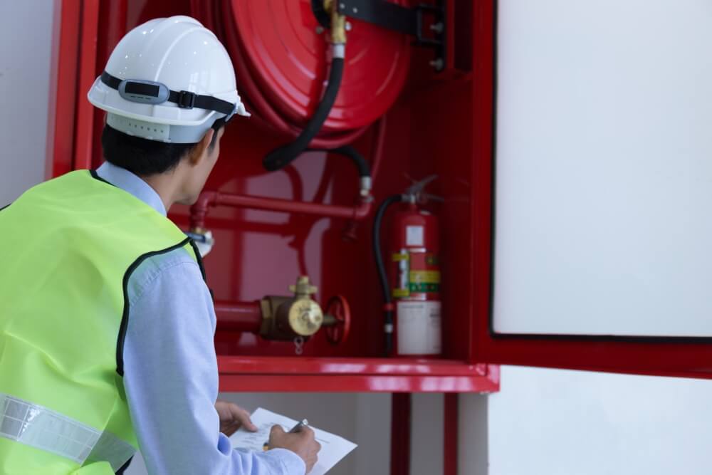 Technician inspecting fire safety equipment indoors, RTek Fire Solutions.