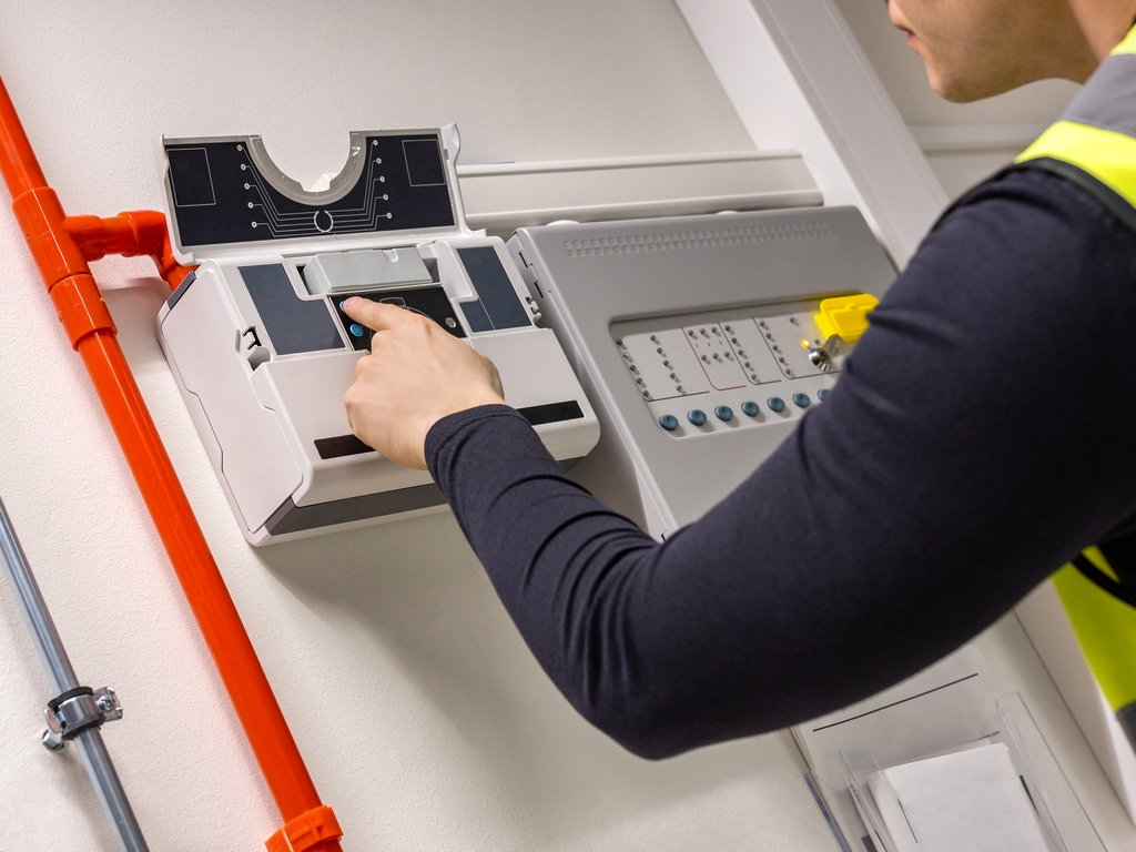 Technician checks smoke detector in data center, RTek Fire Solutions.