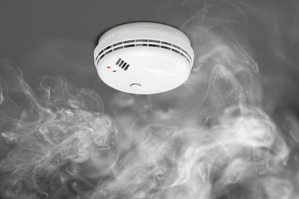 Smoke detector with smoke, RTek Fire Solutions.